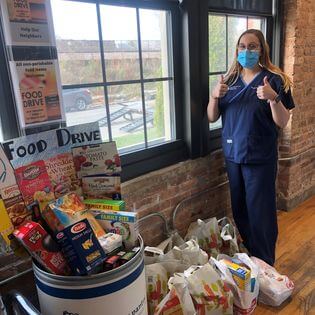 Woman from Ravenswood Chiropractic in front of Food Drive donation bin