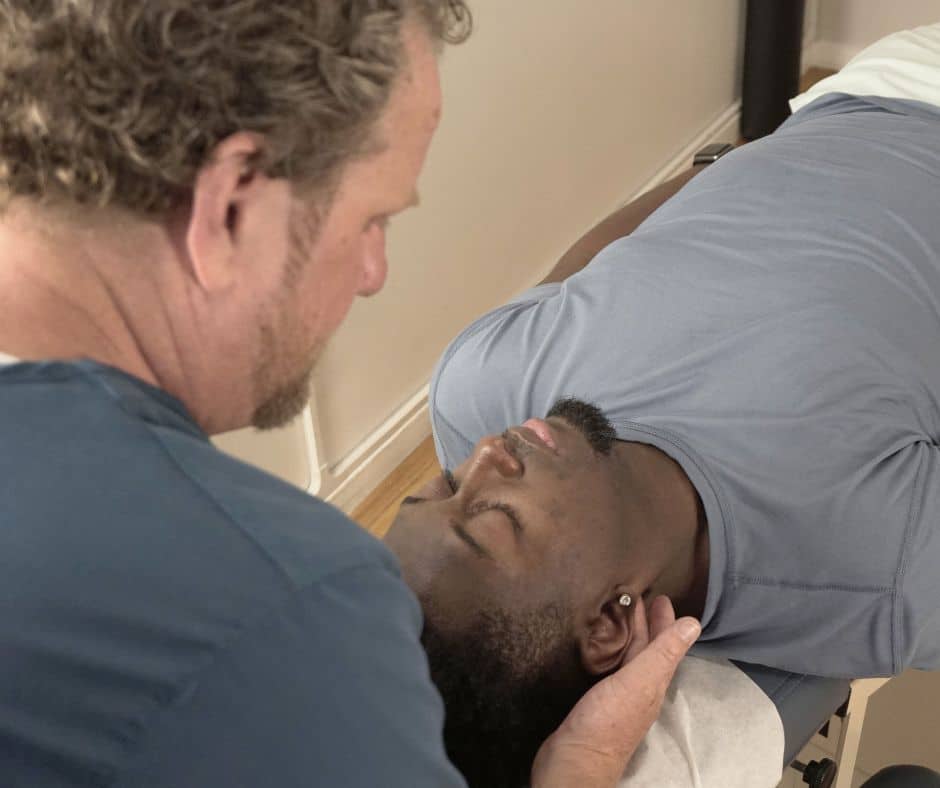 Chiropractor adjusting the cervical spine of patient with TMJ pain